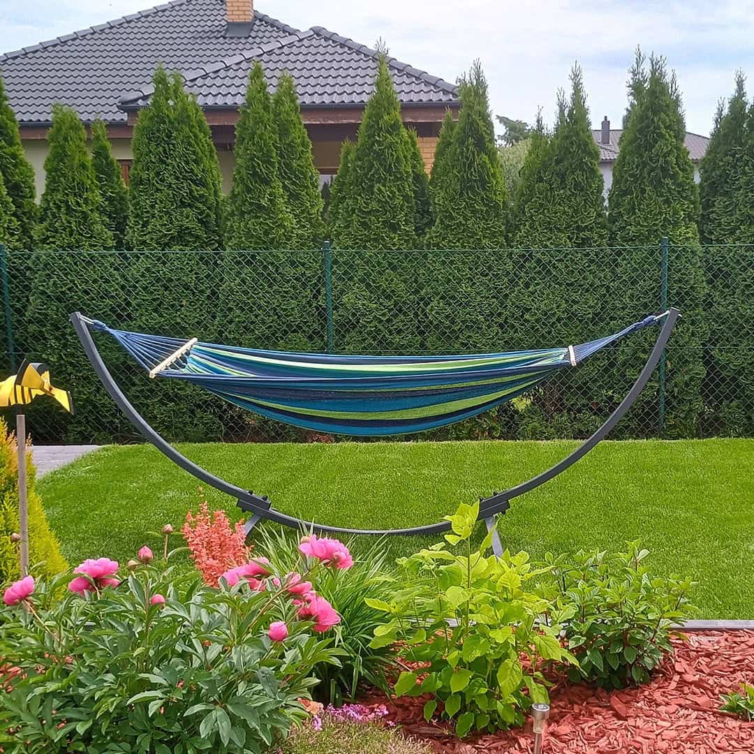 Hamac cu suport din oțel într-o grădină cu flori și gazon tuns